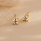 Pair of pearl earrings with gold accents on a beige background, featuring the brand 'eManco'.